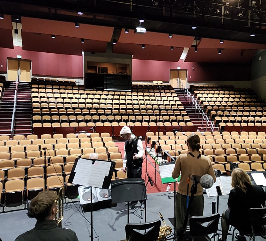 The empty auditorium seen from the stage while musicians rehearse