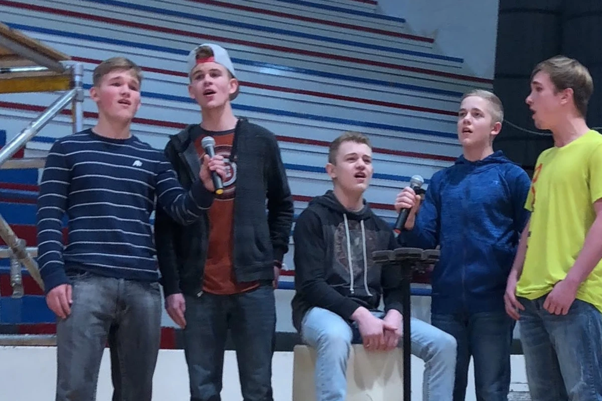 The Belnap Boys singing into microphones in a school gym